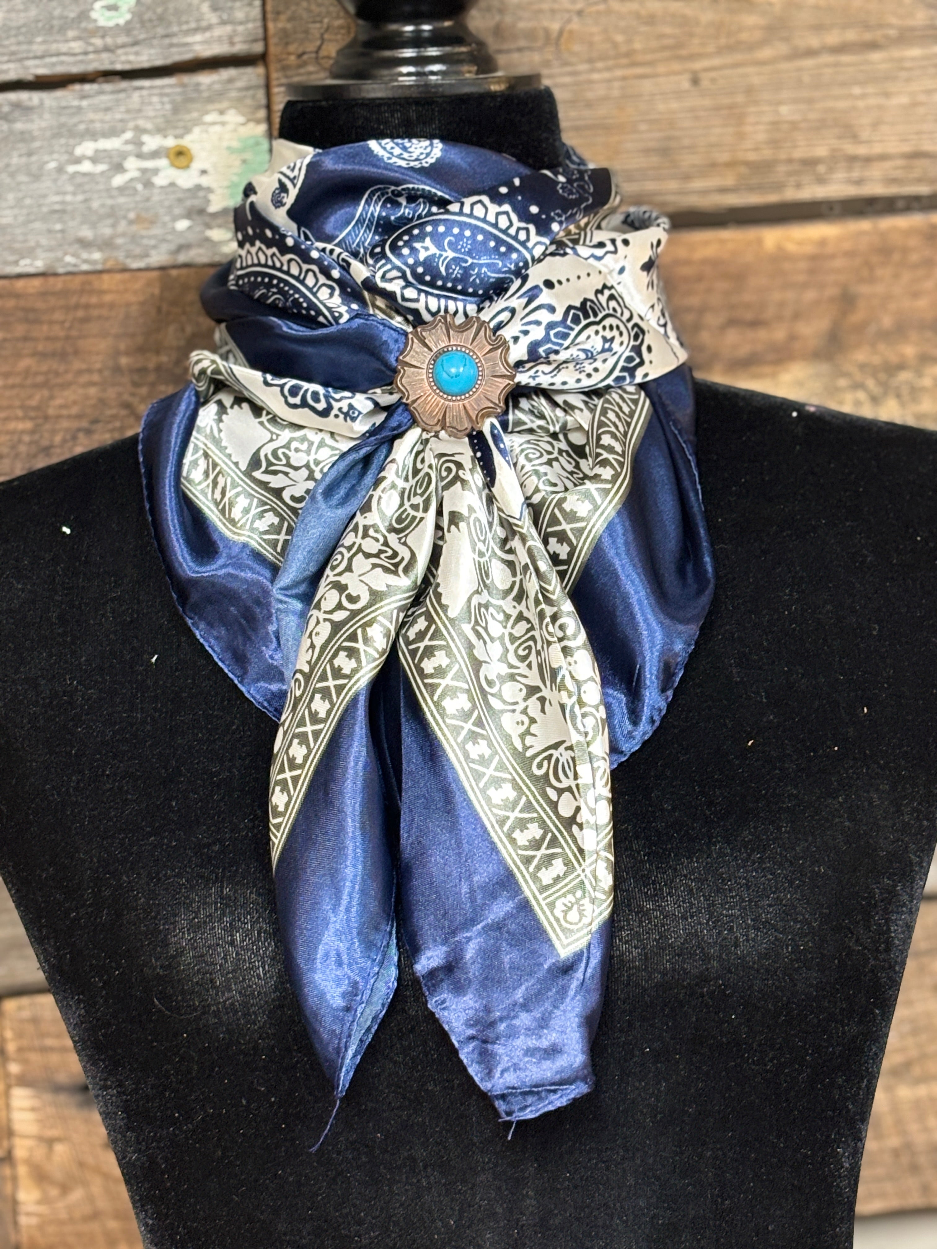 Decorative scarf with brooch on a mannequin against a wooden background